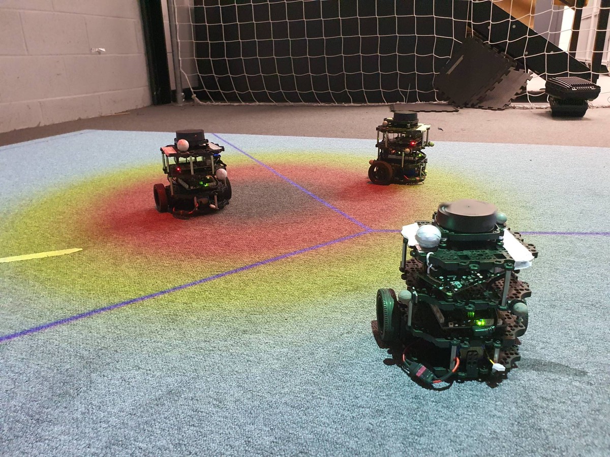 Three ground robots mapping a gas field projected onto the arena floor